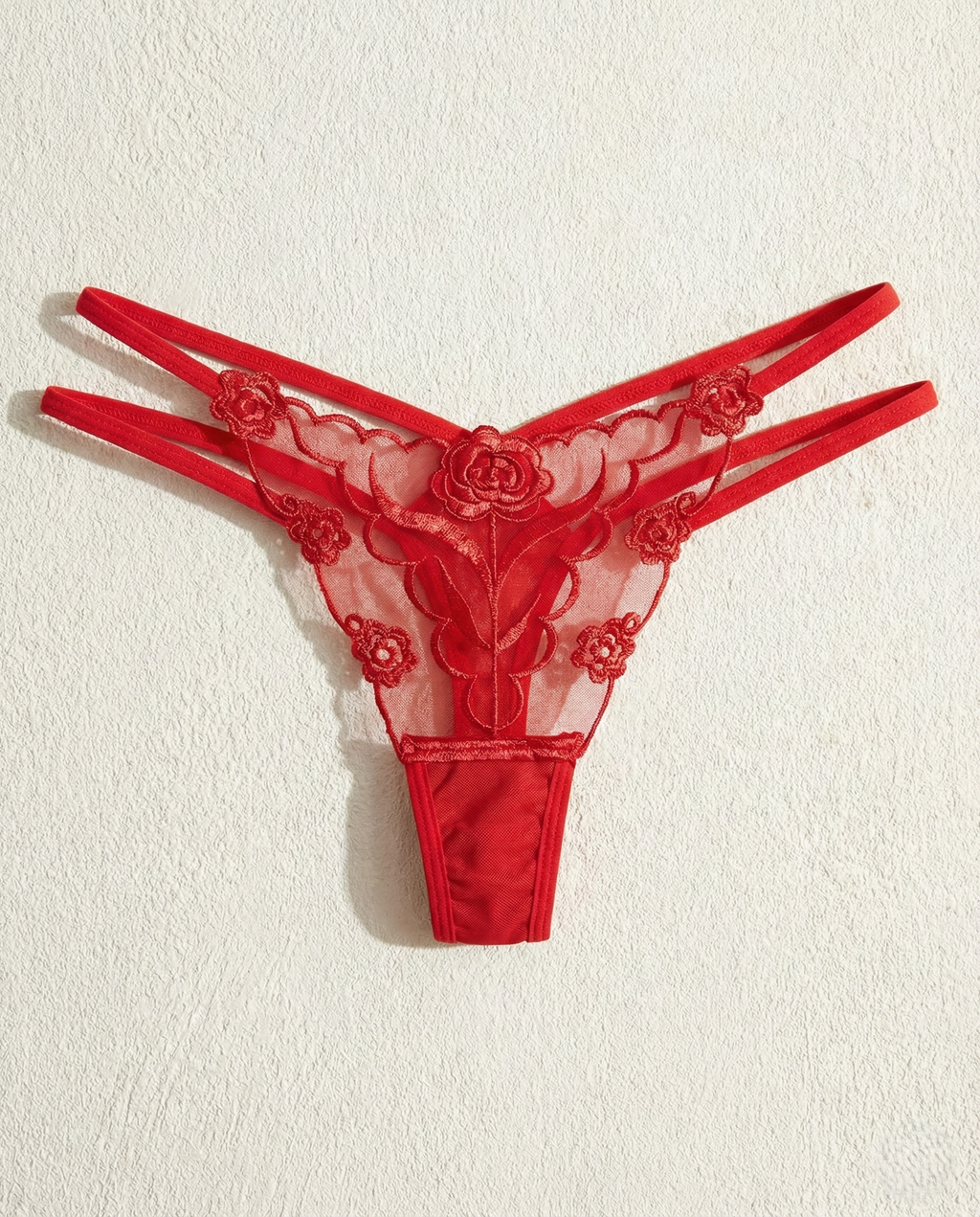 Sheer lace embroidered thong with delicate animal-inspired embroidery and minimal back coverage on mannequin